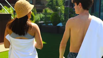 A man and a woman walking on a grassy lawn with a building in the background.