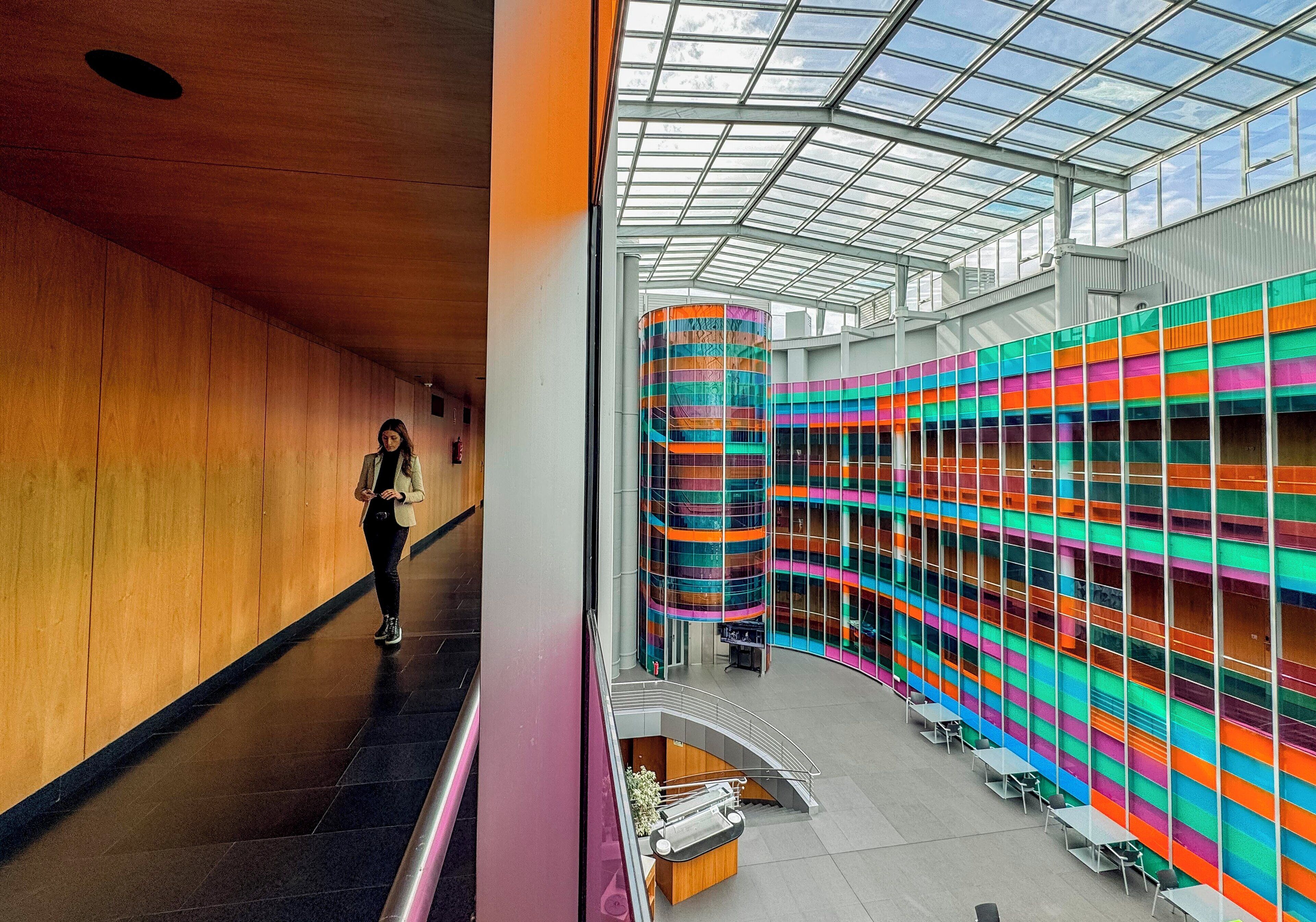 Un edificio moderno con techo de vidrio y una pared interior curva y colorida.