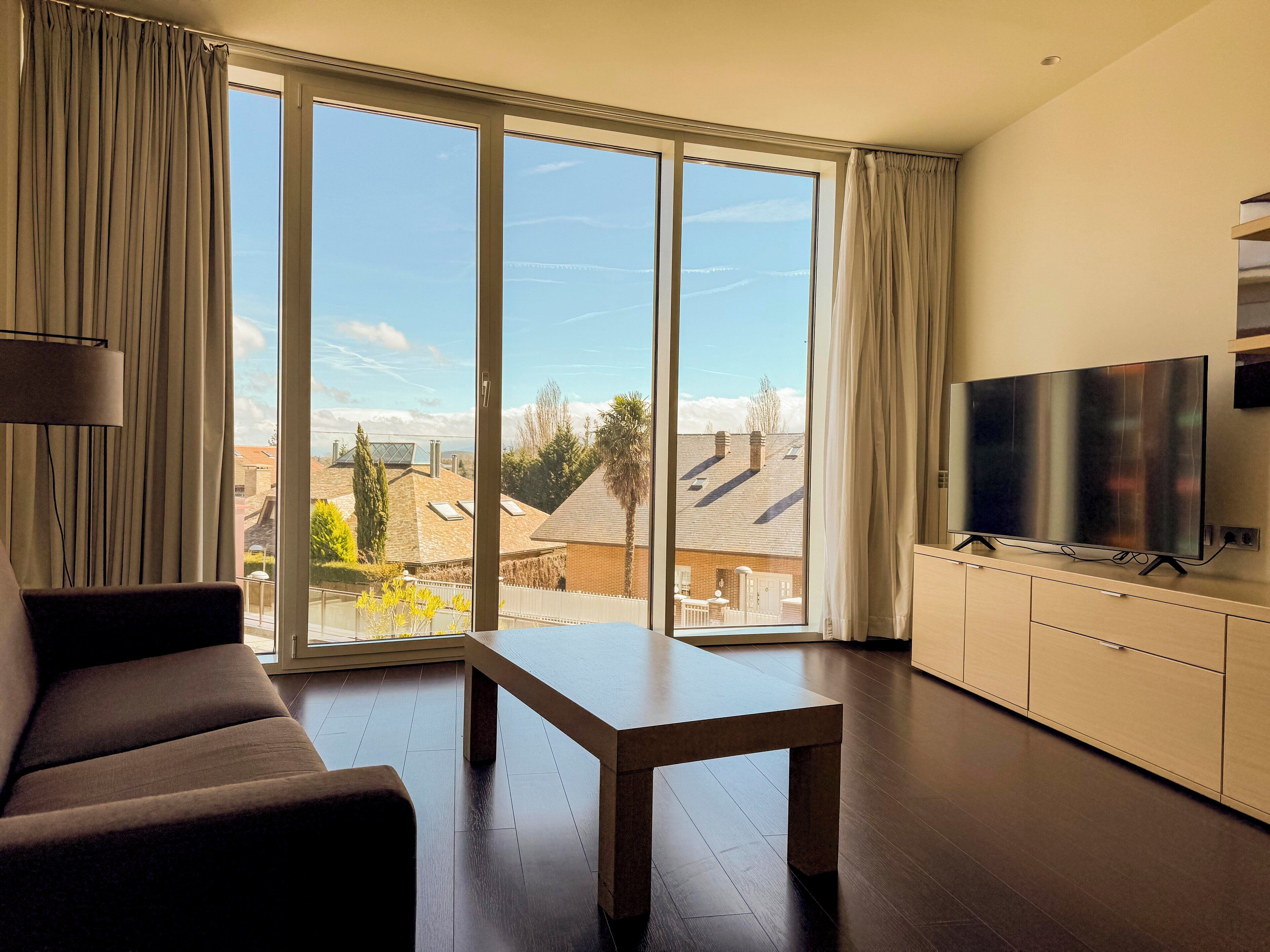 Un salon moderne avec un canapé, une table basse et un téléviseur posé sur un meuble.