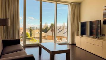 Un salon moderne avec un canapé, une table basse et un téléviseur posé sur un meuble.