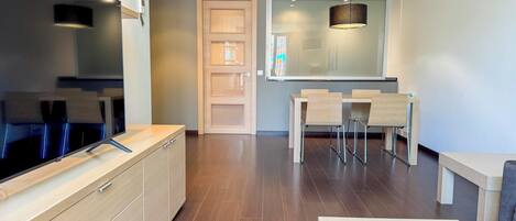 Una cocina moderna con armarios de madera, televisor integrado y comedor con mesa y sillas.