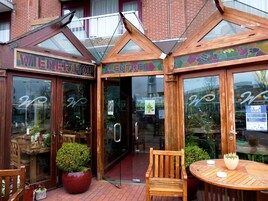 Un restaurante con entrada de vidrio, muebles de madera y un letrero que dice 'Wiener Hof'.