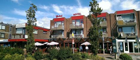 A hotel with multiple floors, outdoor seating areas, and a visible entrance.