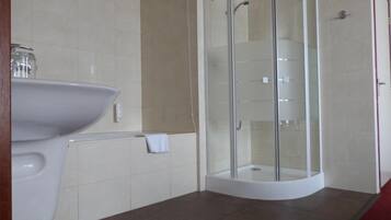 A modern bathroom with a glass-enclosed shower, a white sink, and a tiled floor.