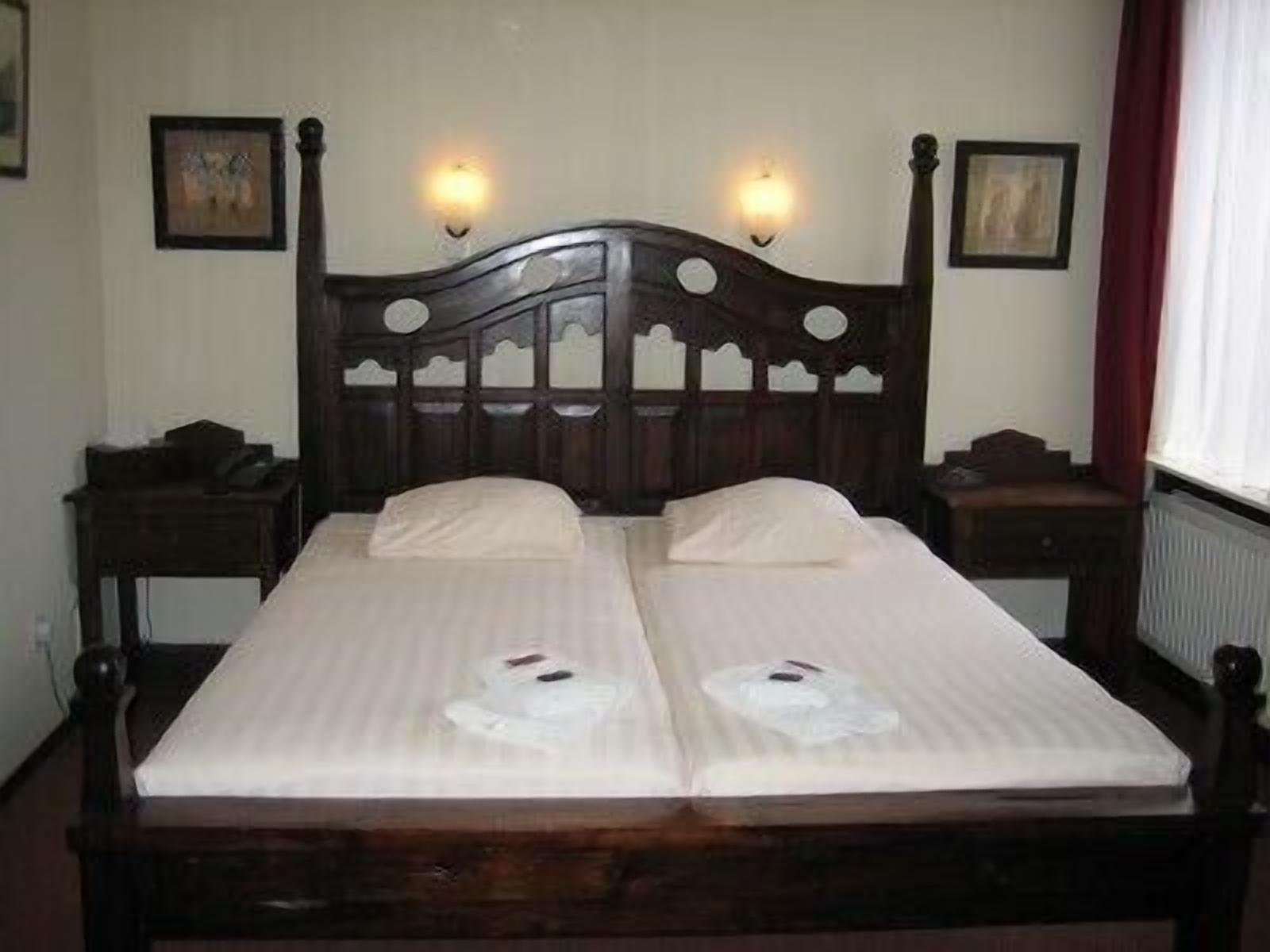 A double bed with a wooden headboard, two bedside tables, and two wall-mounted lamps.