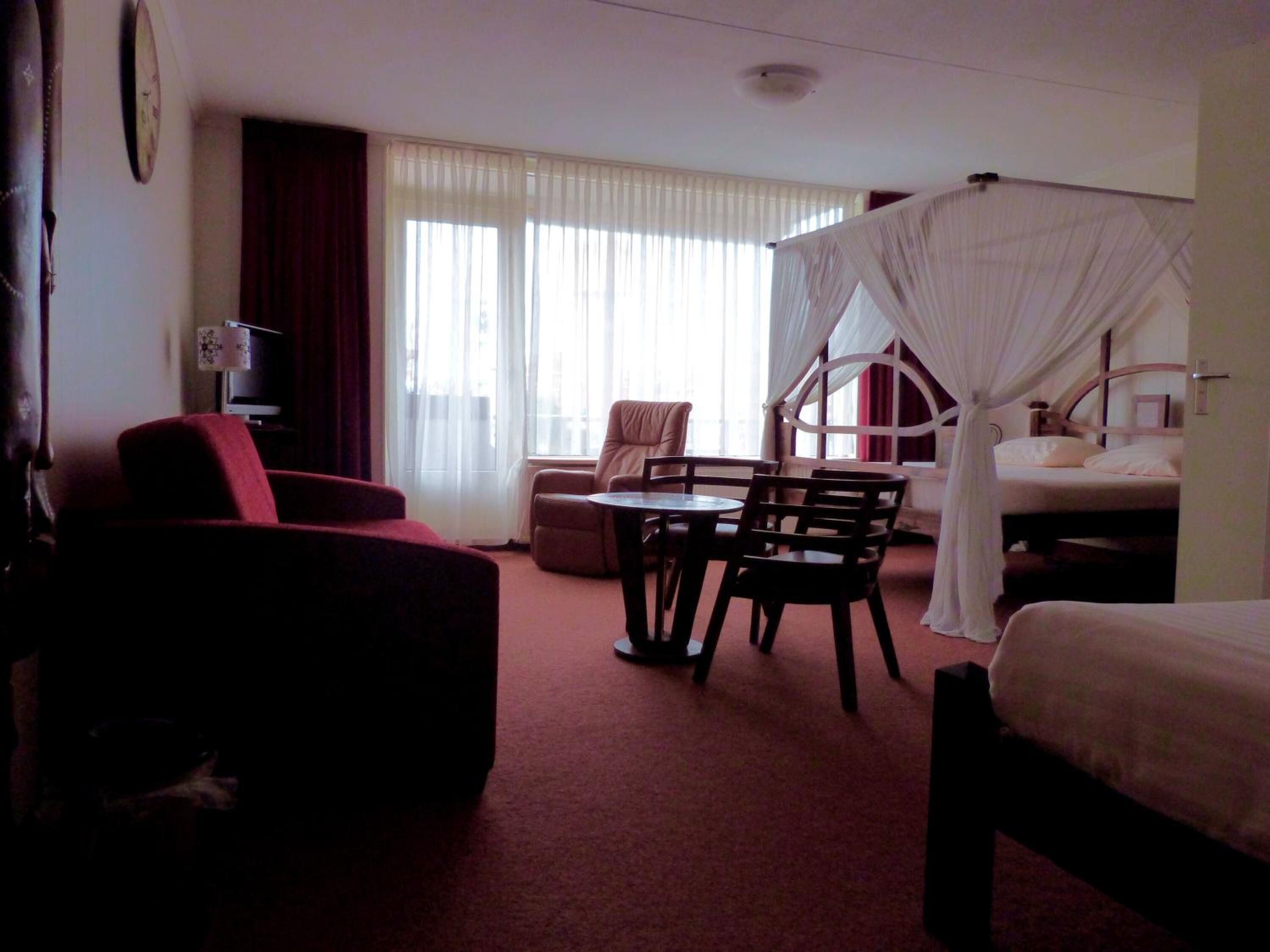 Et hotelværelse med en seng, en stol, et bord og et fjernsyn.