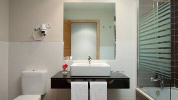 A modern bathroom with a white toilet, a black vanity with a mirror, and a glass-enclosed shower.