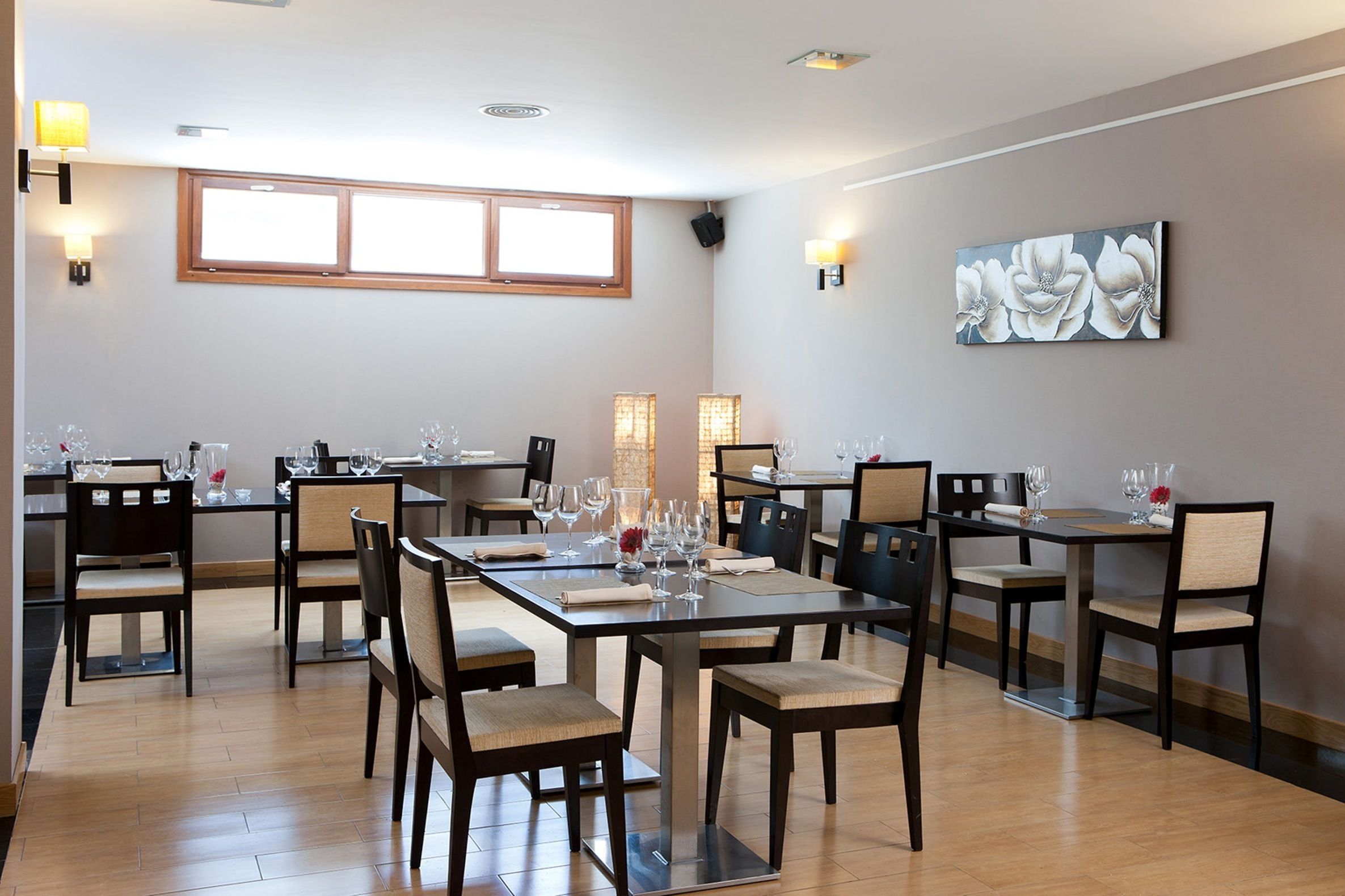 A dining area with multiple tables and chairs, equipped with wine glasses and water glasses.