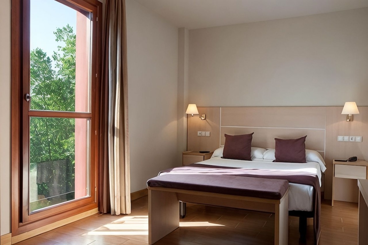Une chambre à coucher moderne avec un grand lit, des lampes de chevet, une table de chevet et une fenêtre avec des rideaux.