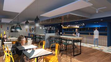 A modern restaurant interior with wooden flooring, yellow and white chairs, and hanging pendant lights.