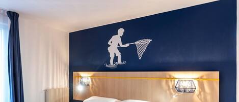 A hotel room with a large bed, two wall-mounted lights, a headboard, and a small yellow basket.