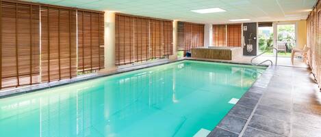 An indoor swimming pool with tiled flooring, wooden blinds, and a bench area.