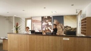 A reception desk with a wooden counter, a potted plant, and a large poster. - ibis Styles Morlaix (Morlaix)