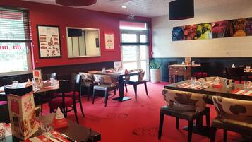 A restaurant interior with red walls, multiple tables, and chairs.
