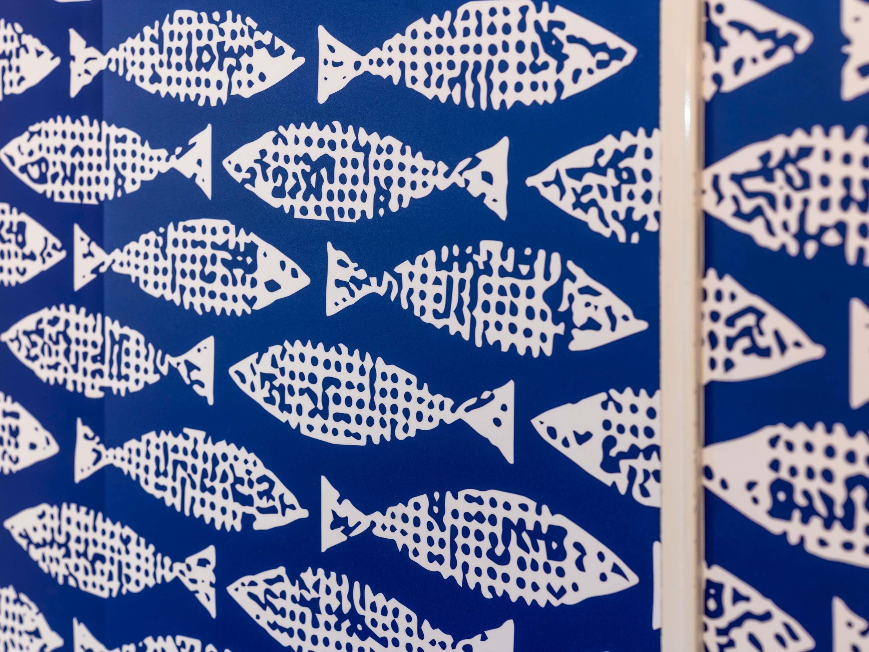 A wall with a pattern of white fish silhouettes on a blue background.