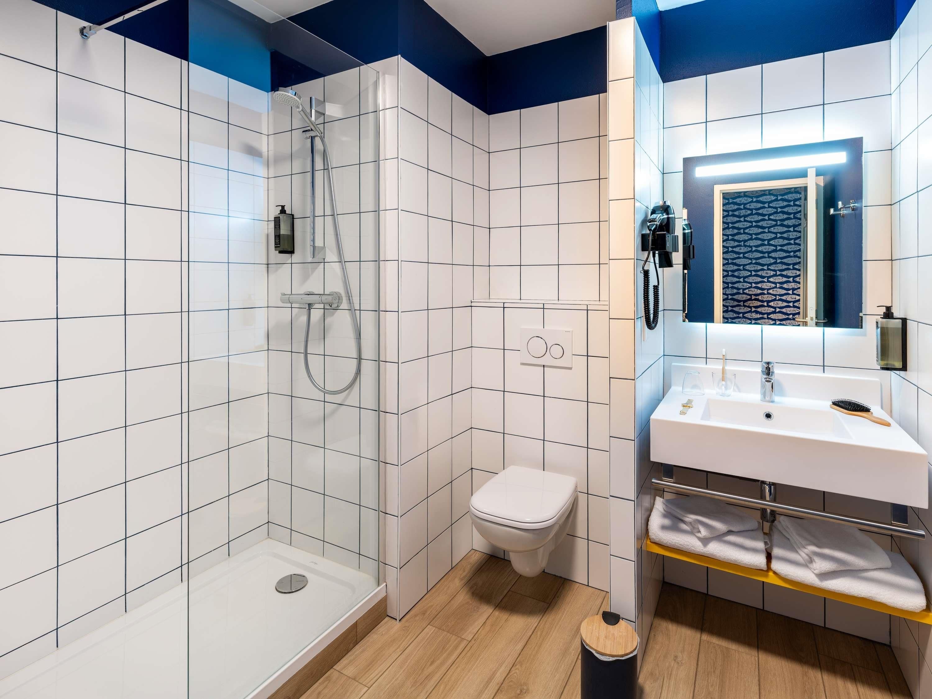Uma casa de banho moderna com chuveiro, sanita e lavatório.