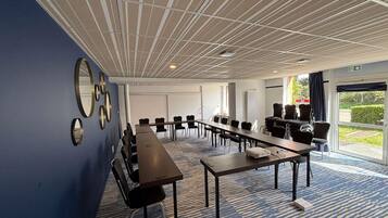 A conference room with a long table, multiple chairs, and a patterned carpet.