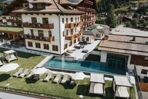 Un hôtel doté d’une grande piscine extérieure, de nombreux balcons avec des garde-corps en bois et d’un espace pelouse bien entretenu.