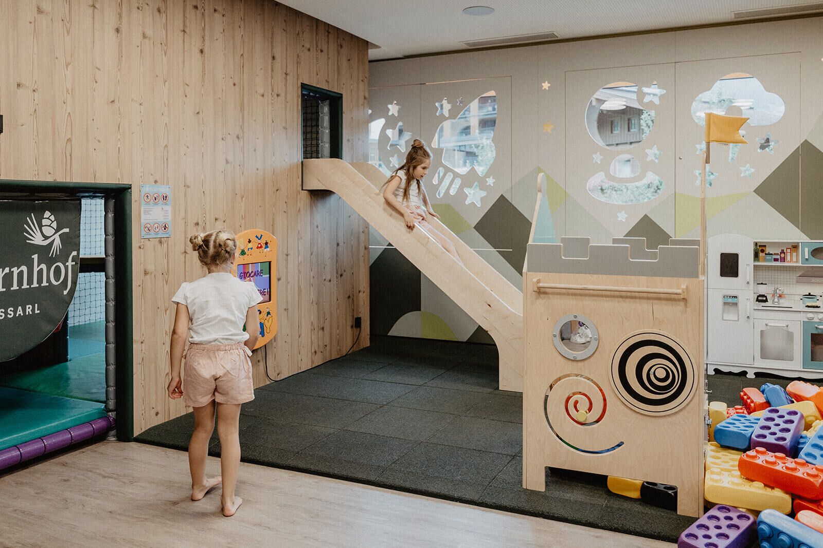 Un área de juegos con un tobogán, una casita y una pared de escalar.