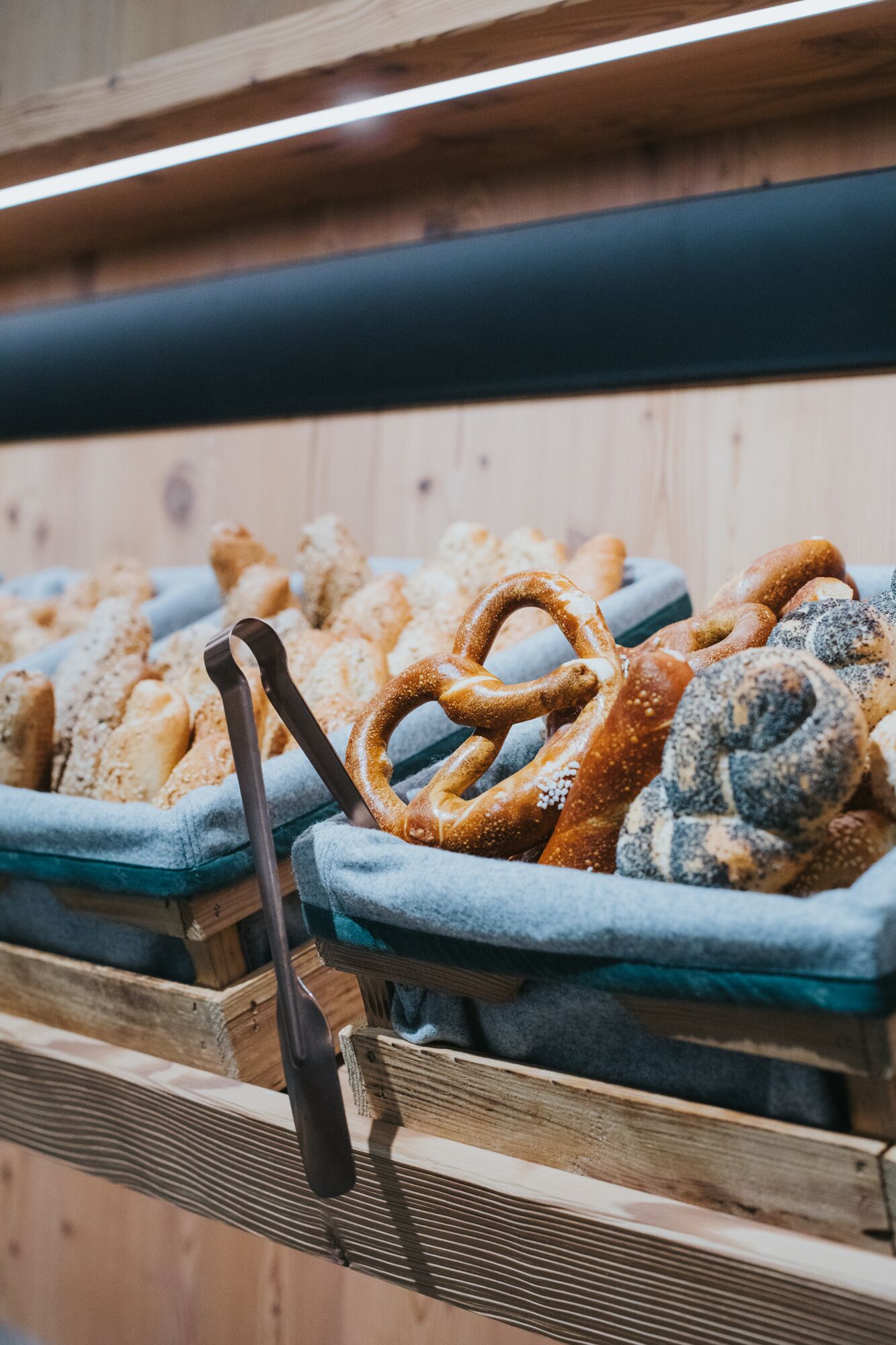 Una exhibición de diversos productos horneados, como pretzels y pan, sobre manteles azules en un escaparate de madera.