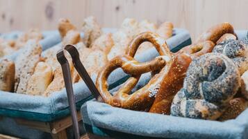 Una exhibición de diversos productos horneados, como pretzels y pan, sobre manteles azules en un escaparate de madera.