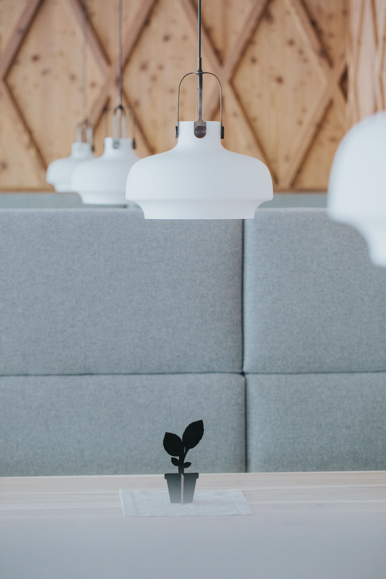 Ein modernes Interieur mit grau gepolsterten Sitzmöbeln und weißen Pendelleuchten.