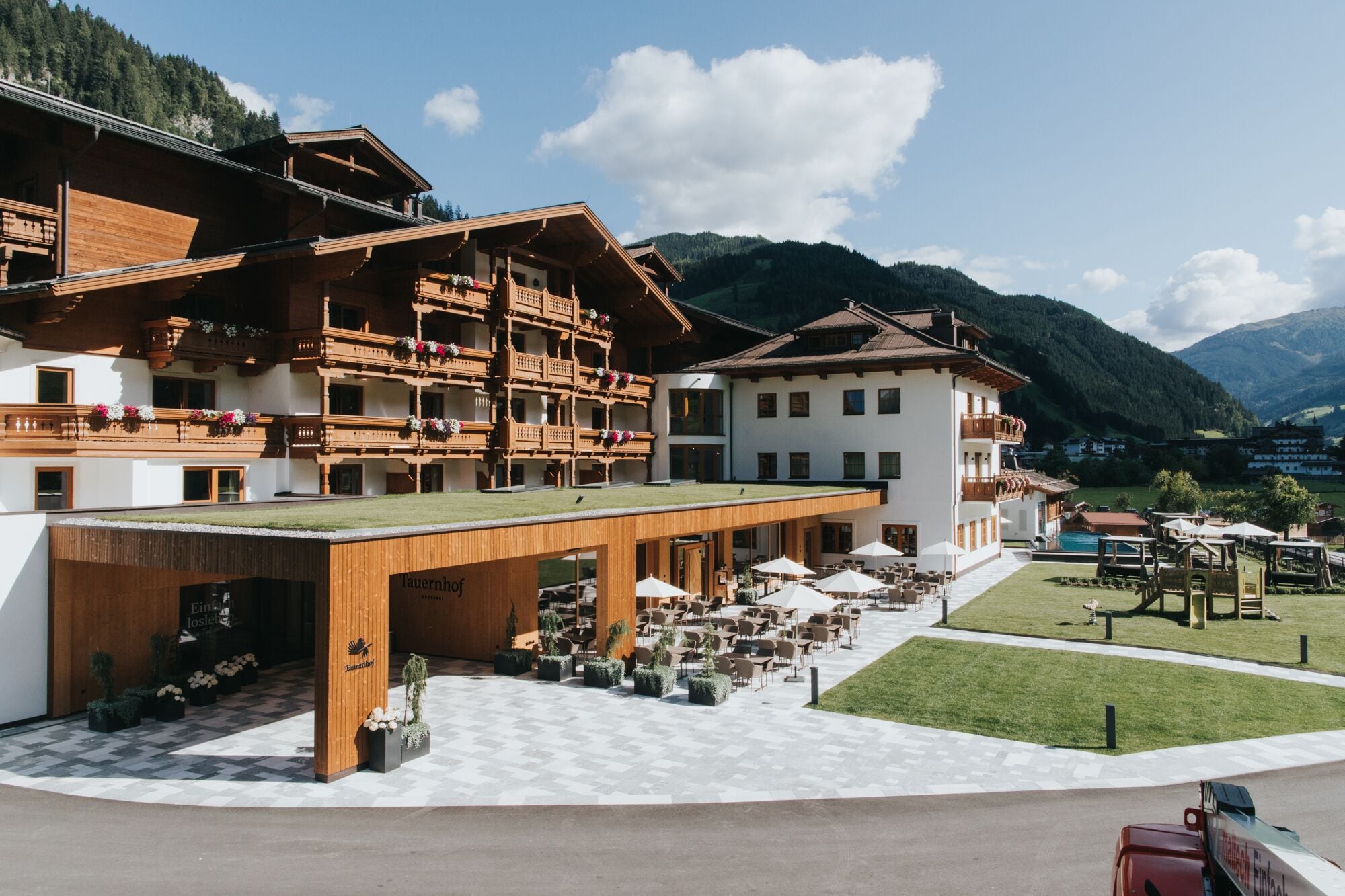 Un hotel con fachada de madera, zona de estar al aire libre y piscina.