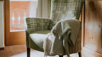 A plaid armchair with a blanket, positioned near a wooden door and a window with curtains.