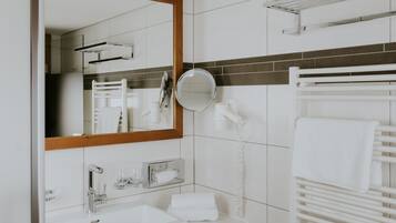 A modern bathroom with a white sink, mirror, and towel rack.