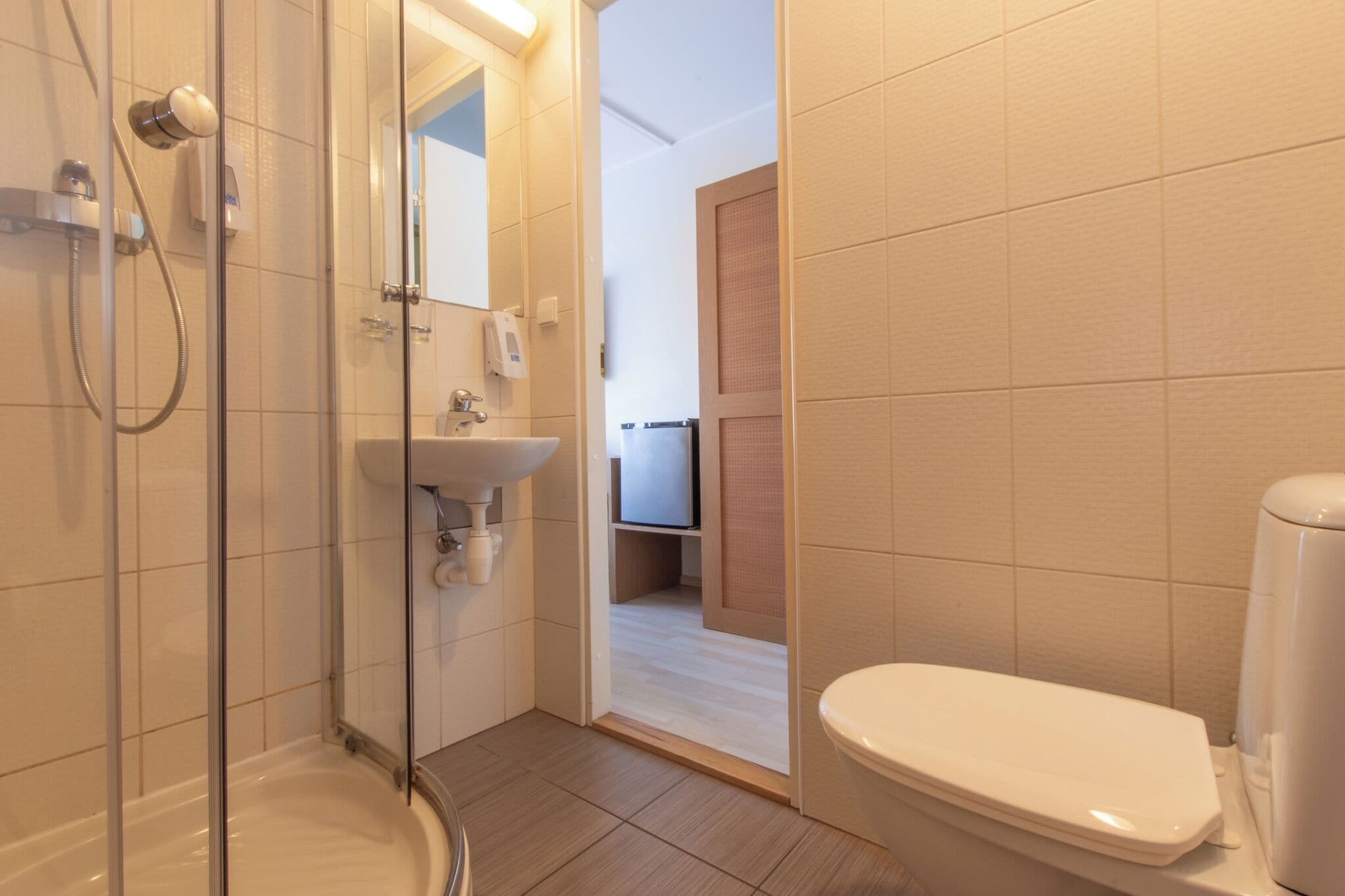 Un bagno con cabina doccia in vetro, lavandino e water.
