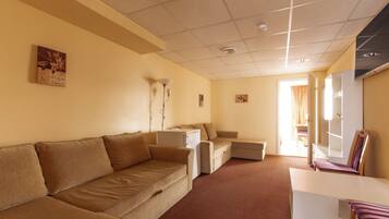 A room with a beige sofa, a small white table, a chair, and a cabinet.