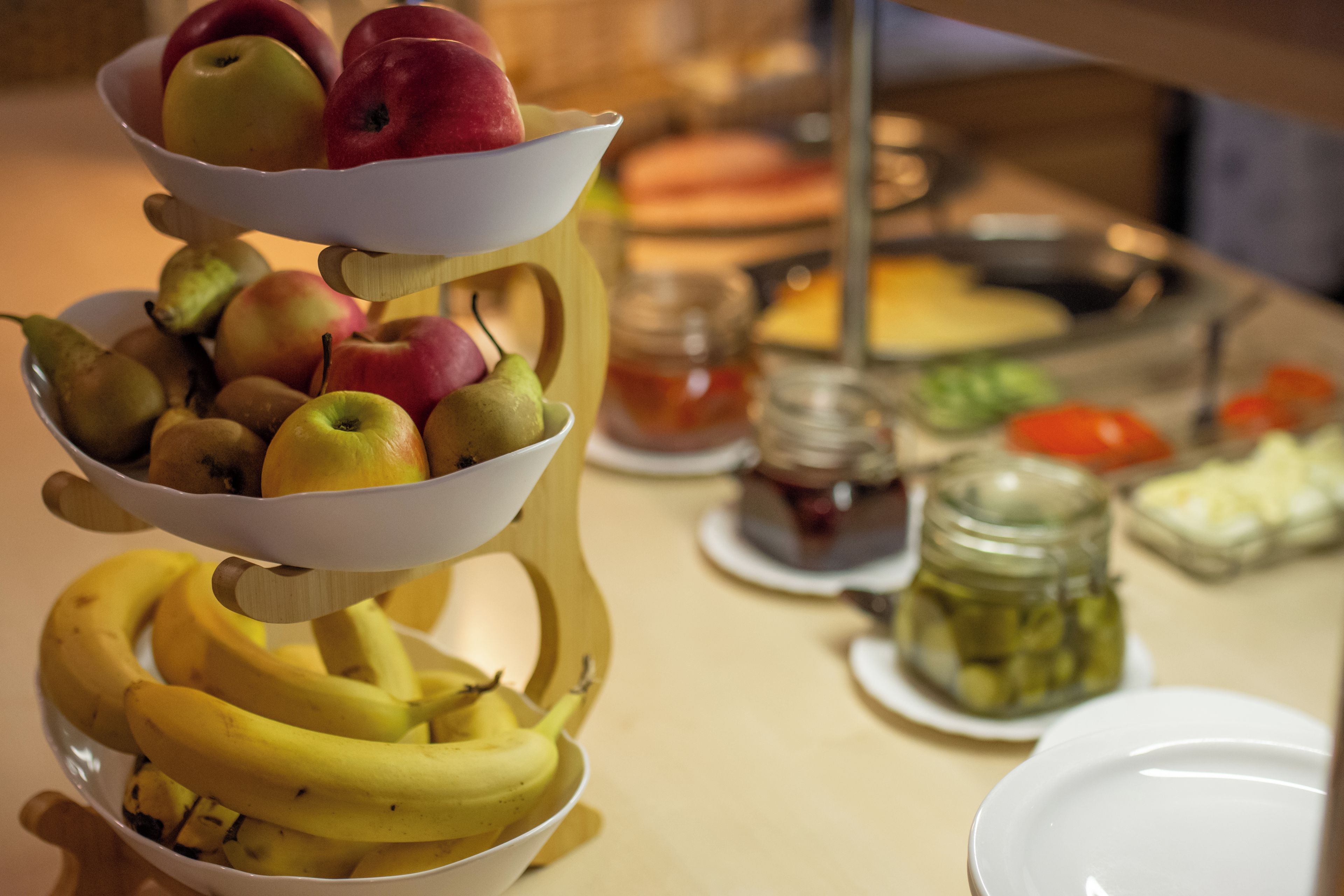 Disposició de fruita sobre una taula, amb un plat, un bocal i un bol al fons.