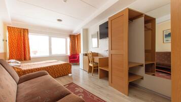 A room with a bed, a desk, a chair, a TV, and a wardrobe.