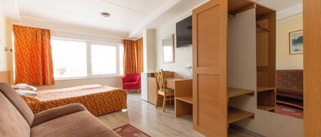 A room with a bed, a desk, a chair, a TV, and a wardrobe.