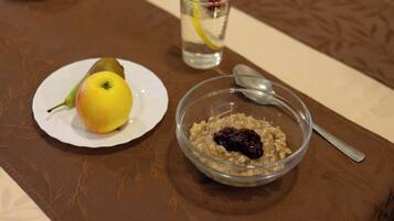 Una mesa de comedor con un plato de comida, un vaso de agua y un tazón de avena con fruta.