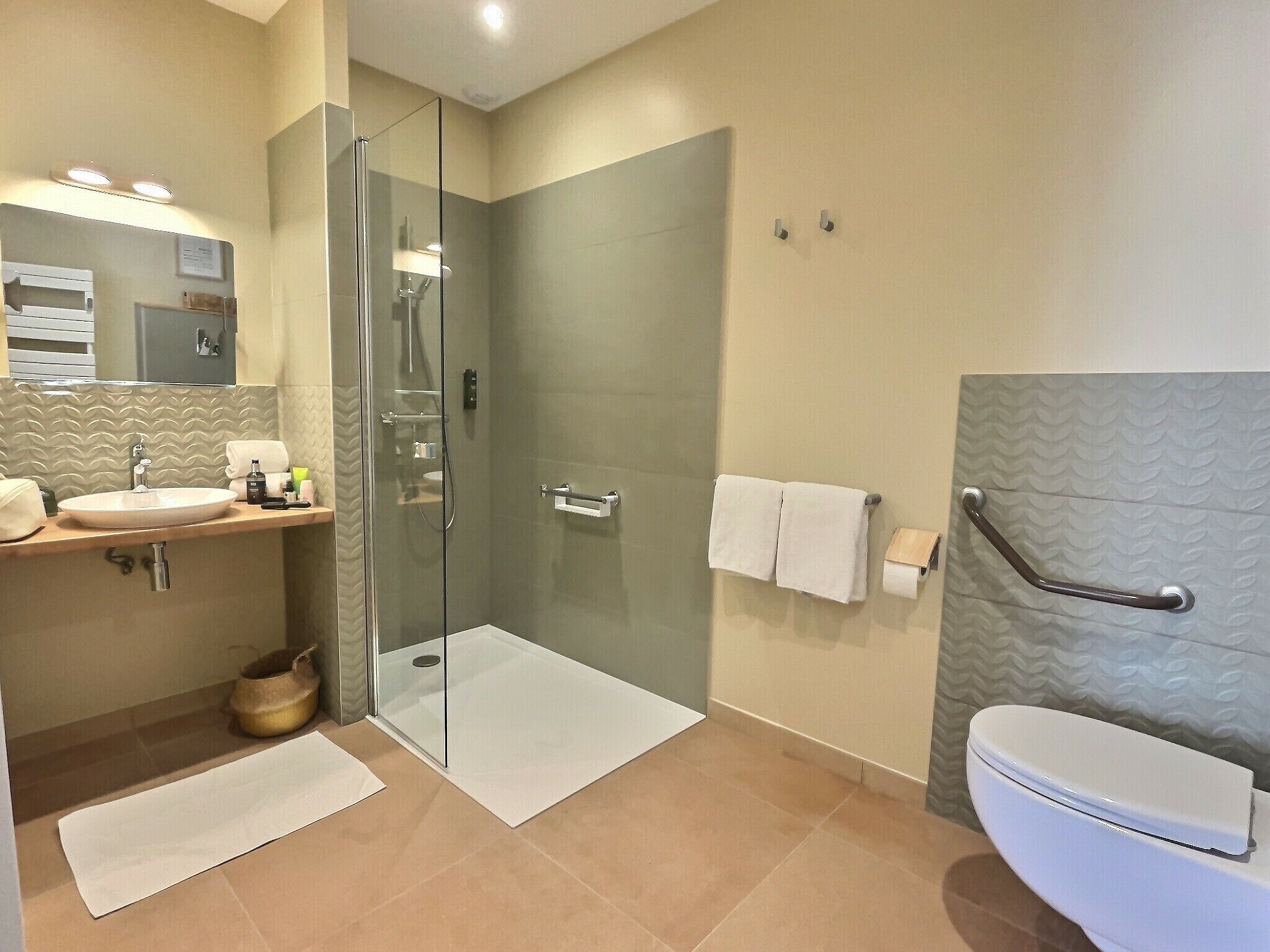 Un baño moderno con ducha de vidrio, lavamanos blanco y retrete.