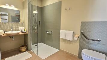 Un baño moderno con ducha de vidrio, lavamanos blanco y retrete.