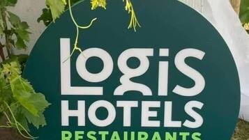 A circular sign with the text "Logis Hotels Restaurants" and "Depuis 1948" indicating the establishment's name and year of operation.