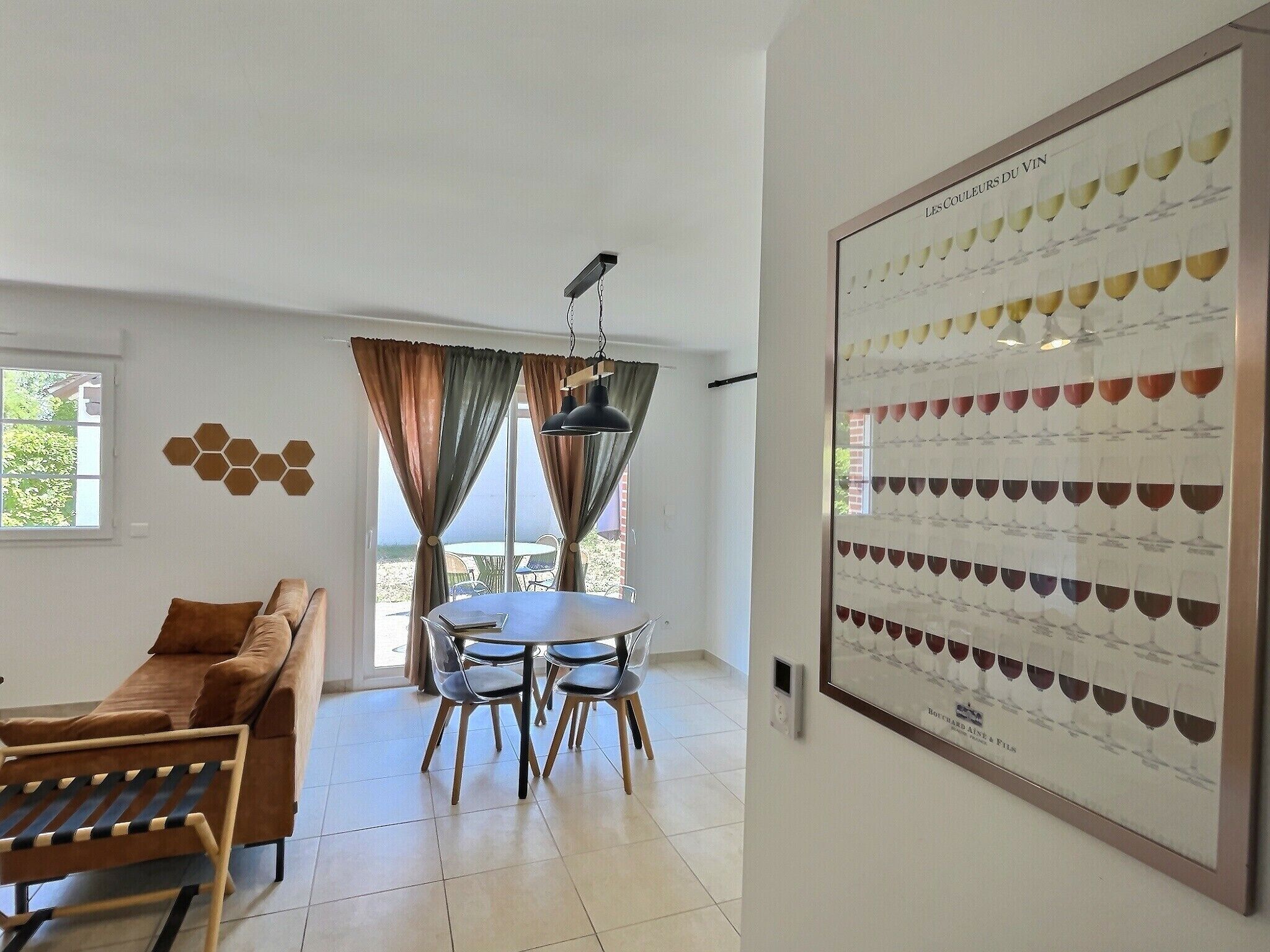 Un interior moderno con una zona de comedor, un sofá y un panel en la pared para organizar copas de vino.