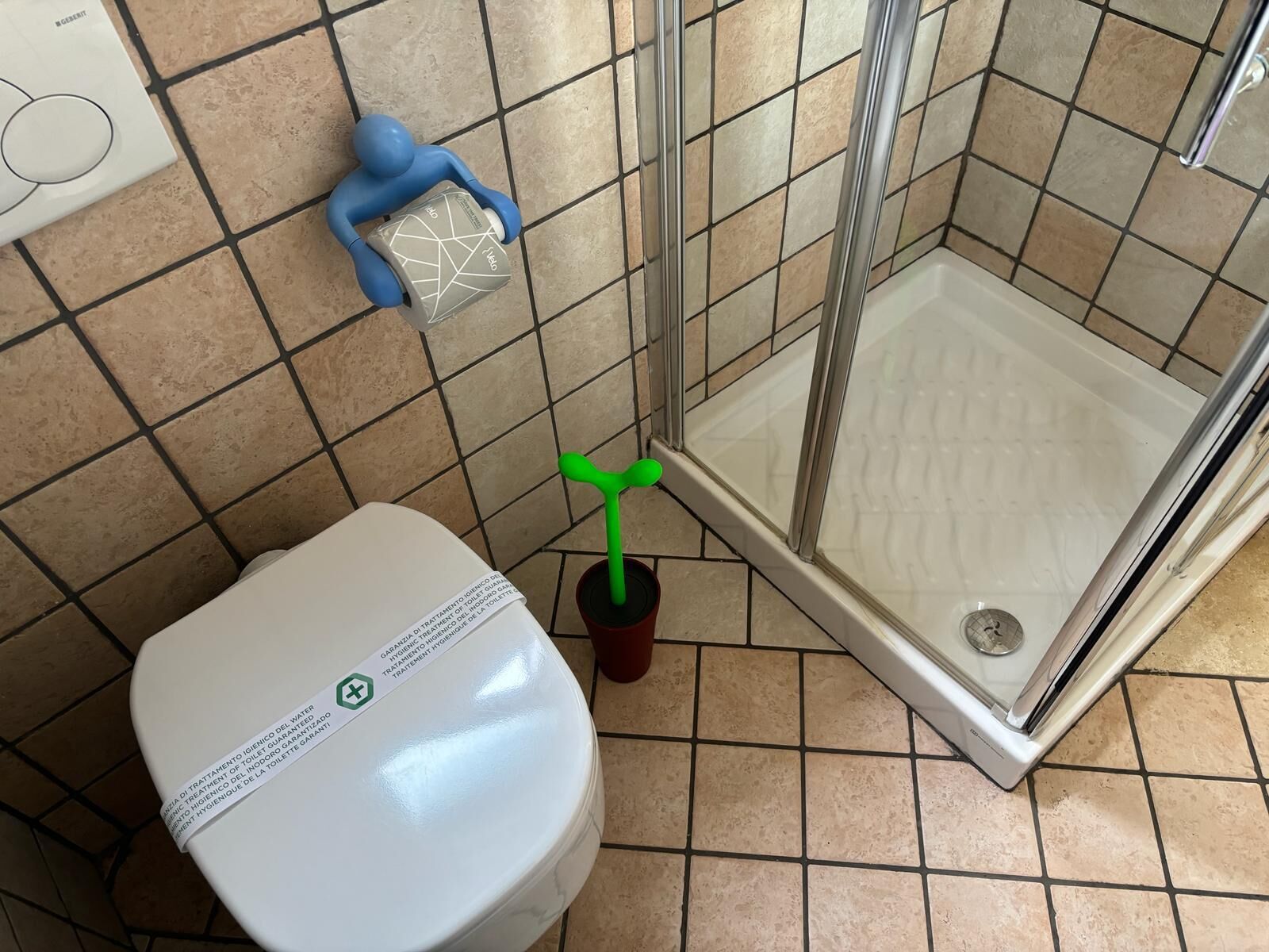 Ein Badezimmer mit Toilette, Dusche und Fliesenboden.