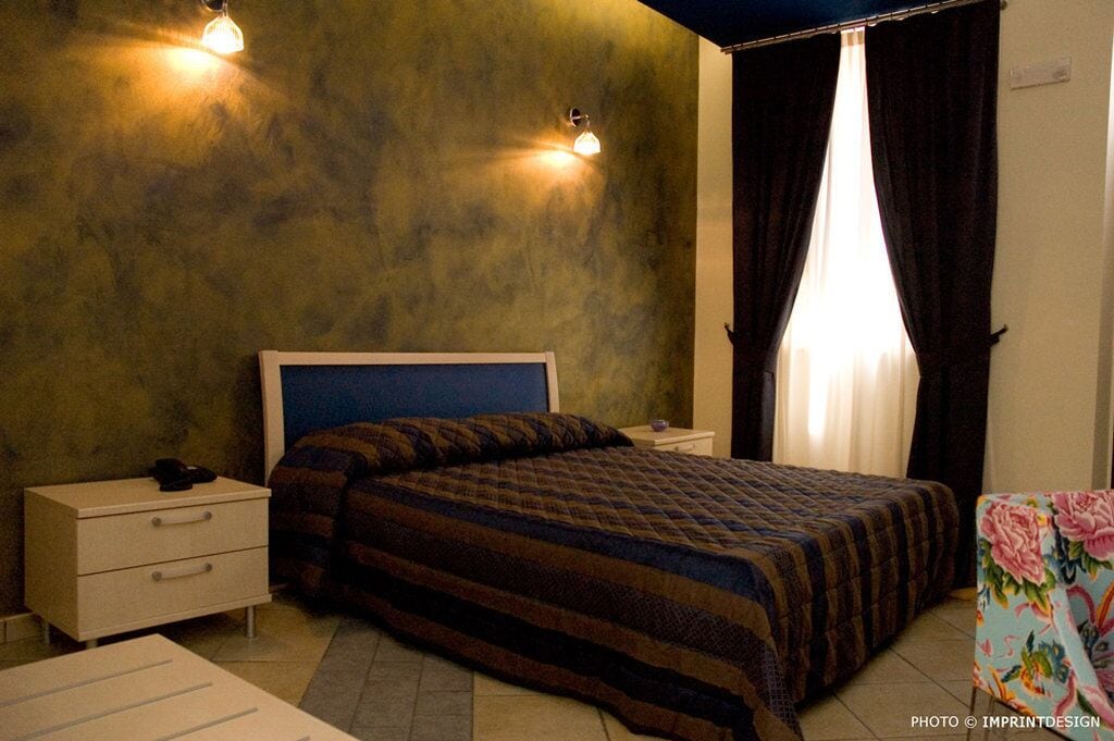 Ein Schlafzimmer mit Bett, Nachttischen, einem Schminktisch und einem Fenster mit Vorhängen.