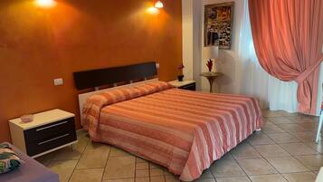 Un dormitorio con cama, mesitas de noche, una pequeña mesa y una lámpara de pared.