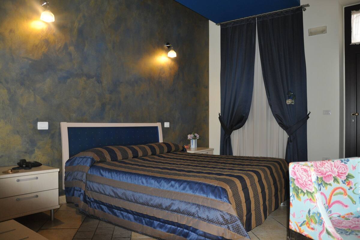 Ein Schlafzimmer mit Bett, Nachttisch und Vorhängen.