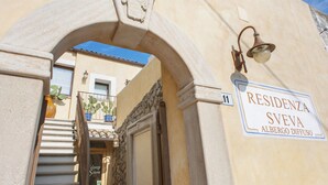 A building entrance with a stone archway, a street sign, and a lamp post. - Residenza Sveva (Termoli)
