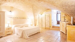 A bedroom with a vaulted ceiling, a bed, a wardrobe, and a nightstand with a lamp. - Residenza Sveva (Termoli)