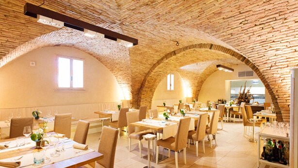 A restaurant with arched brick ceilings, multiple dining tables with chairs, and a view of the city through large windows. - Residenza Sveva (Termoli)