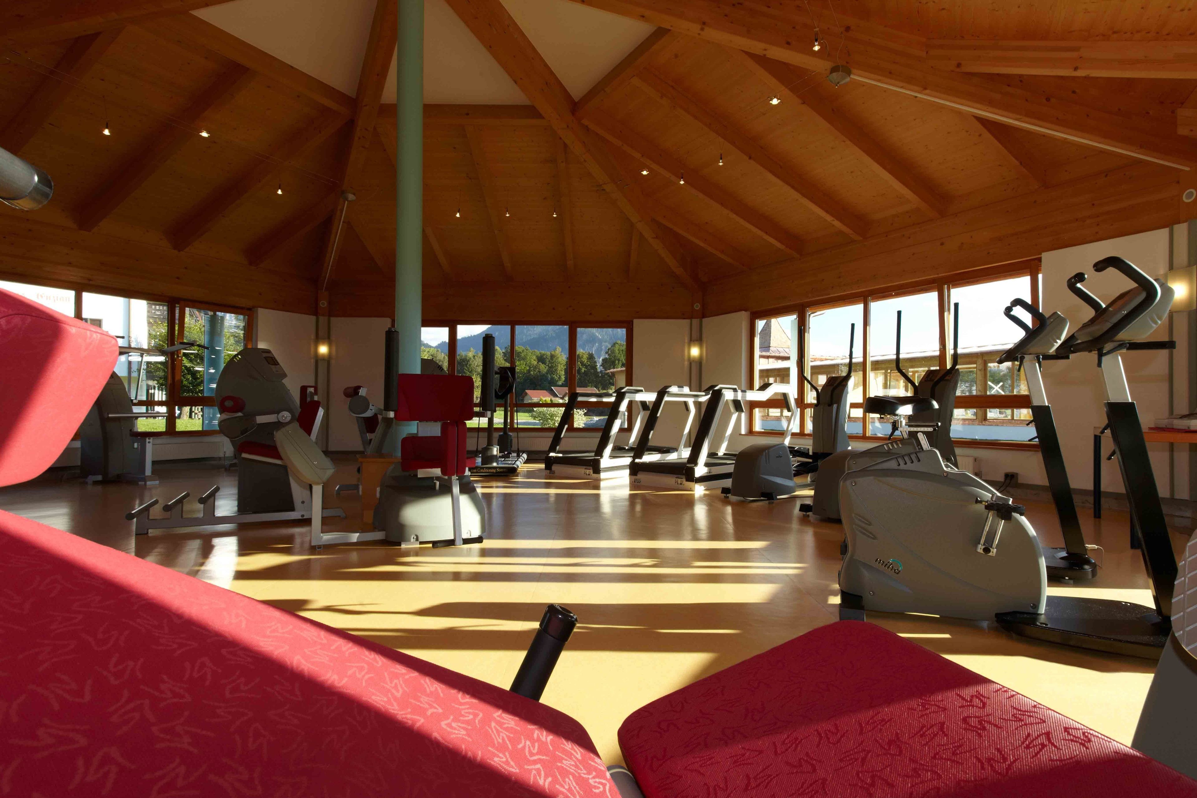 A gym with treadmills, stationary bikes, and red cushioned seating areas.