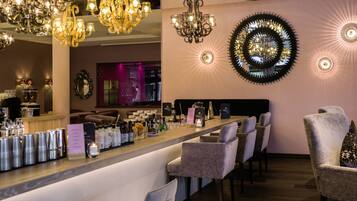 A bar area with multiple seating options, a bar counter with various bottles, and decorative lighting fixtures.