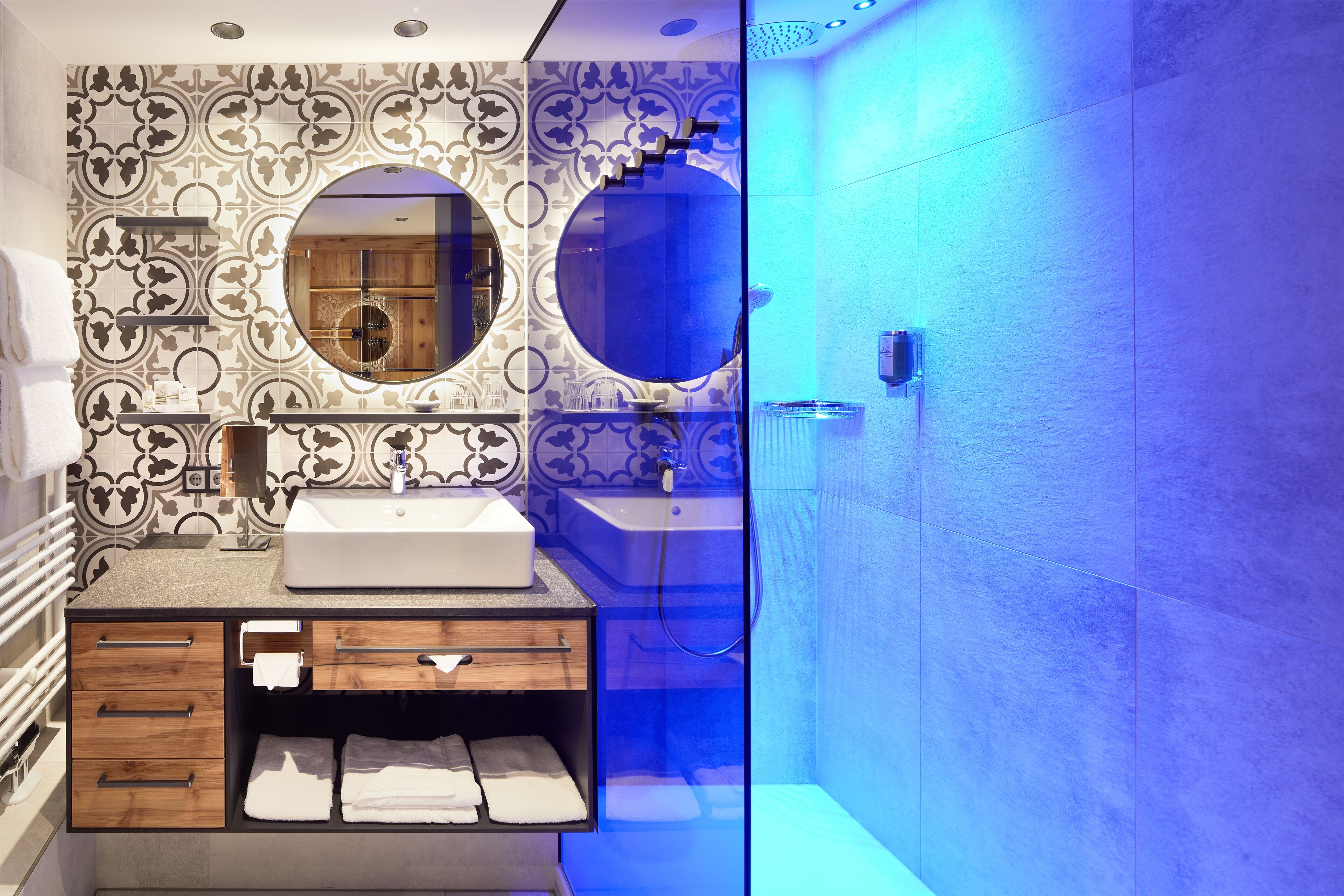 Une salle de bain moderne avec un meuble-lavabo, deux miroirs et un espace douche.