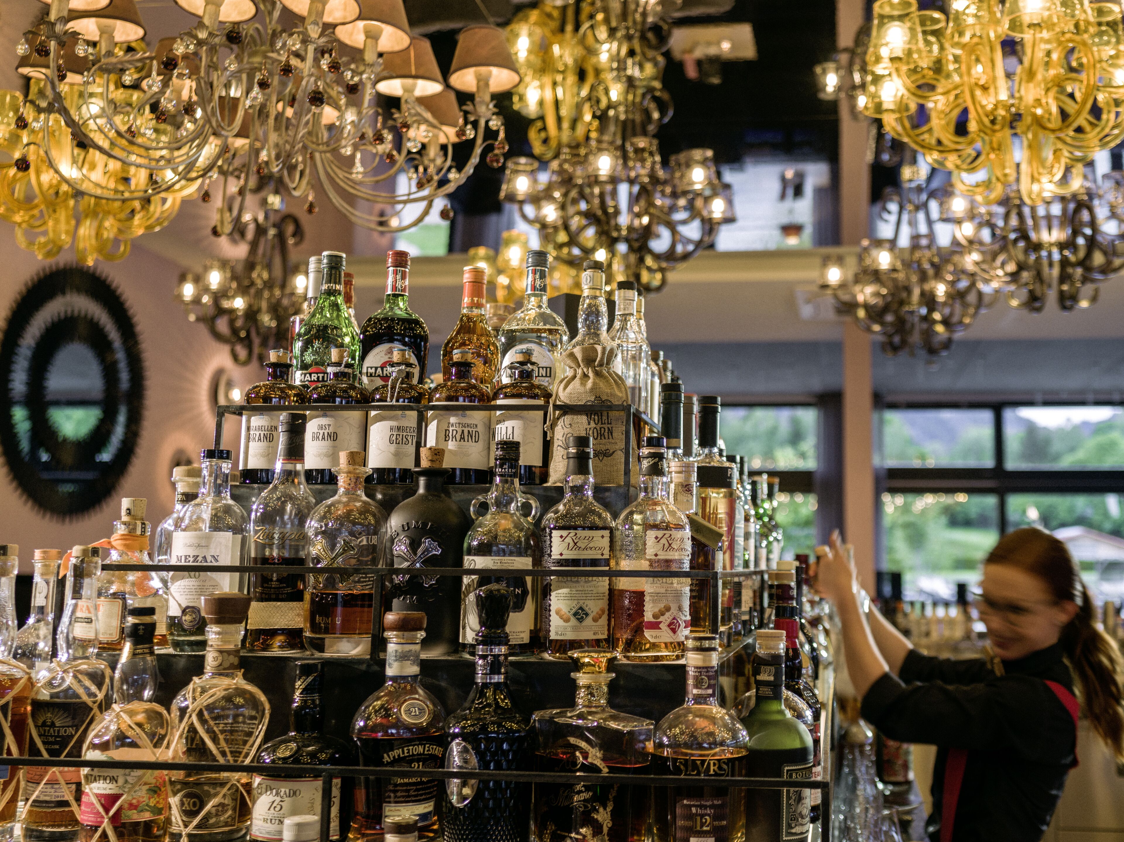 A bar area with a variety of liquor bottles and a chandelier.